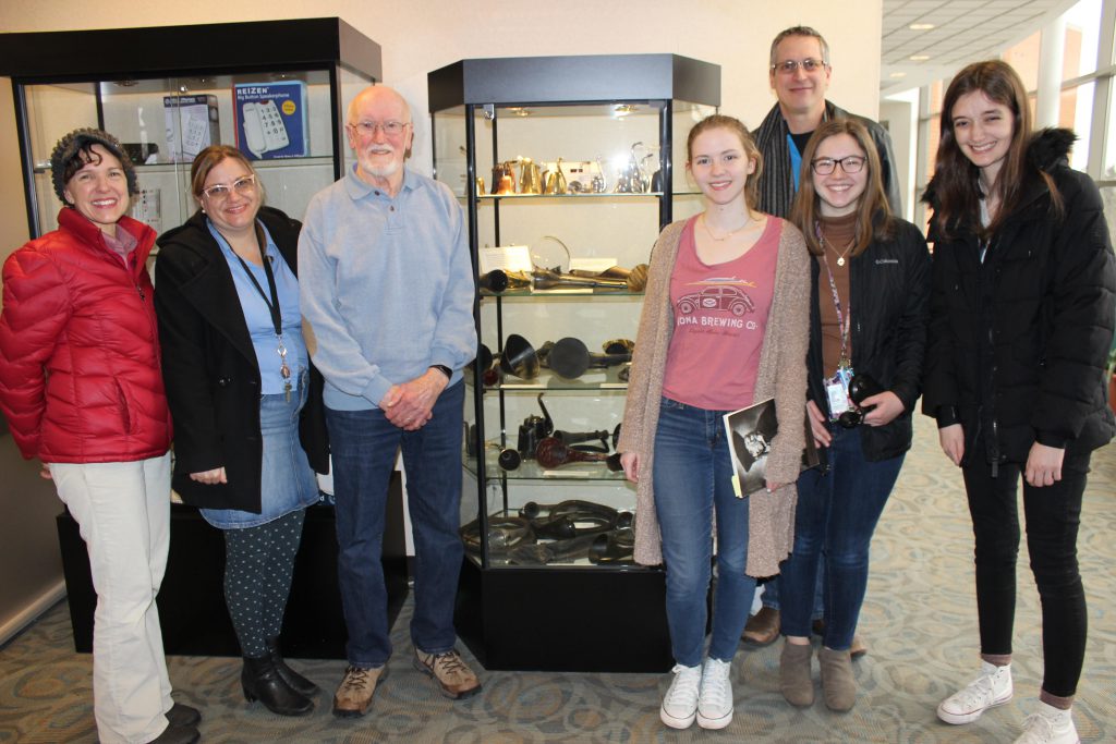 Group Photo at the Department of Audiology at Western Michigan University. The group is posing around a case of ear trumpets. 