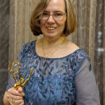 Alumna Kate Loebrich holding an Emmy