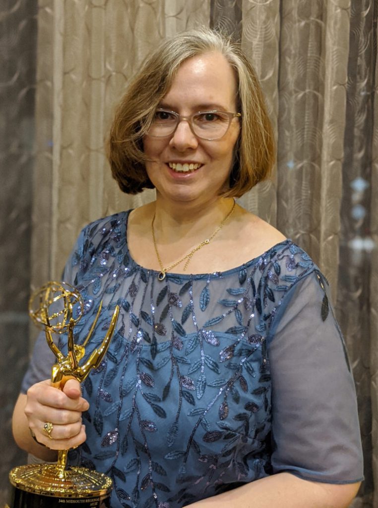 Alumna Kate Loebrich holding an Emmy